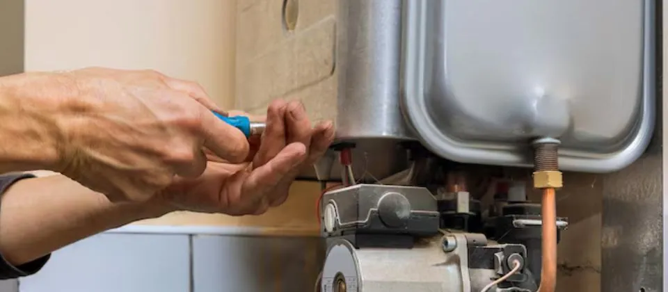 Hands working on a boiler circulator pump and piping