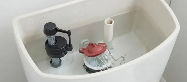 Open toilet tank showing the flapper, chain and fill valve